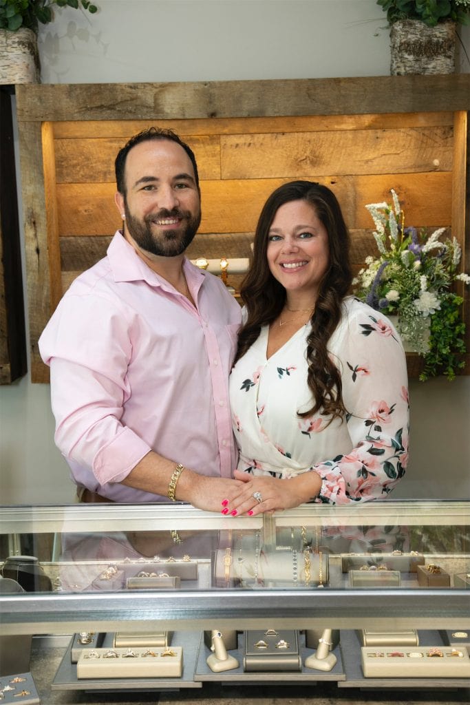 Elegant couple showcasing custom jewelry at Taylor Made Jewelry store, highlighting engagement rings and fine accessories.