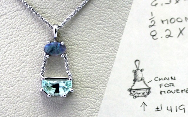 Custom designed necklace pendant next to original design sketch